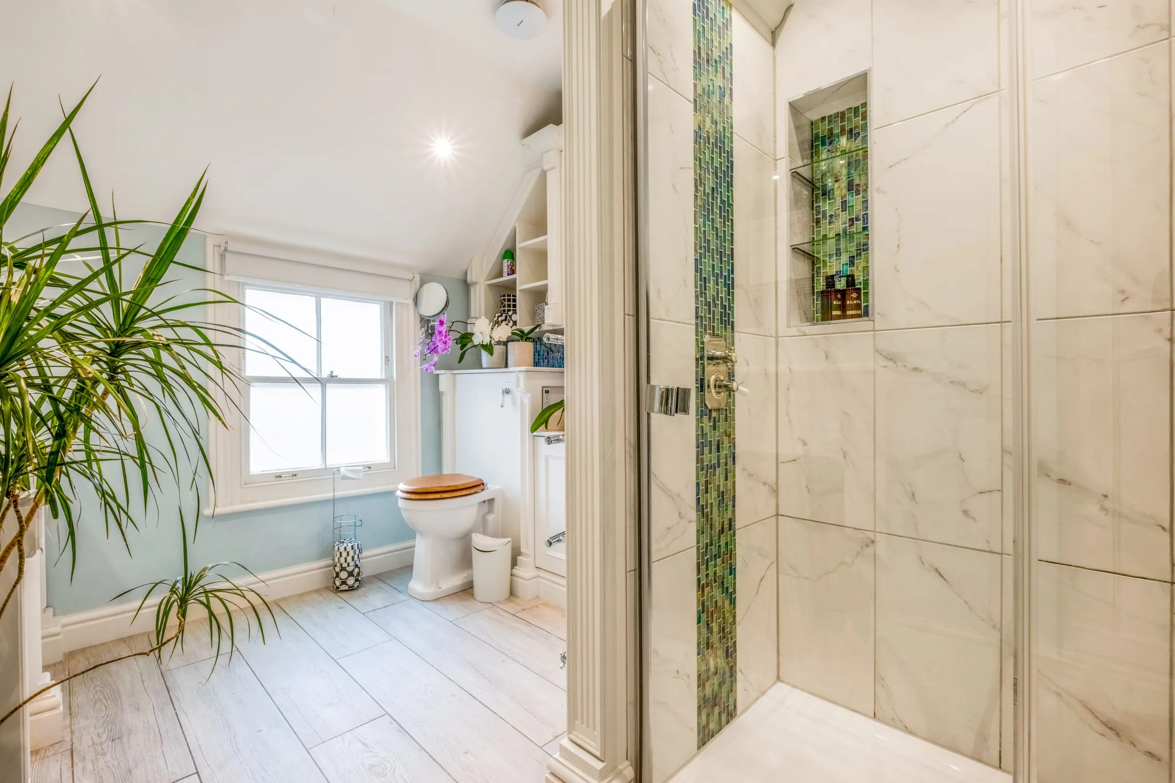Bathroom with a glass-screened shower, marble-effect tiles and a green mosaic feature strip