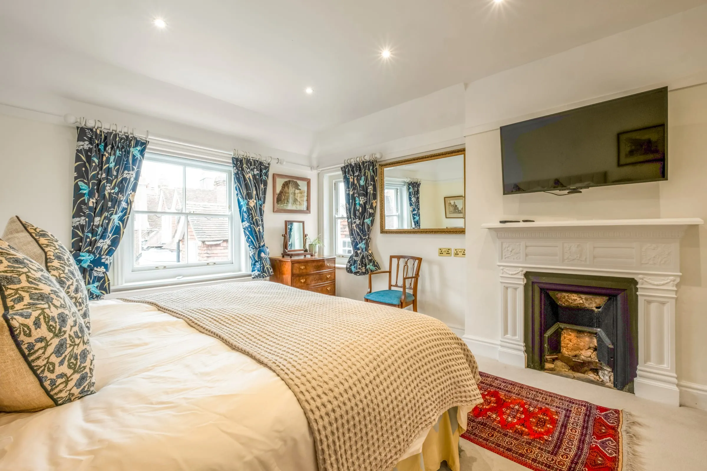 Bedroom with a period fireplace, wall-mounted TV and sash window
