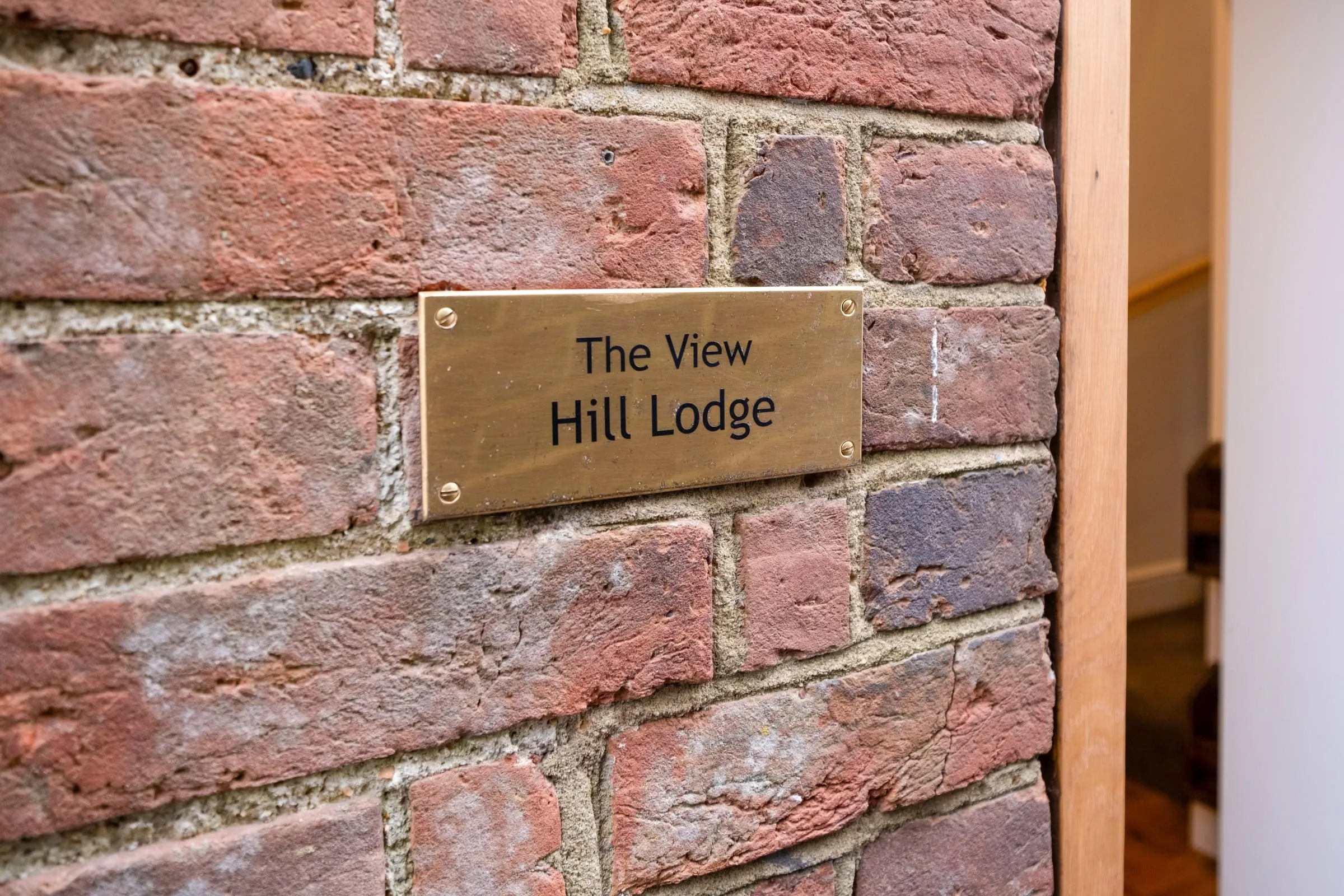 Brass plaque reading The View, Hill Lodge on a red brick wall