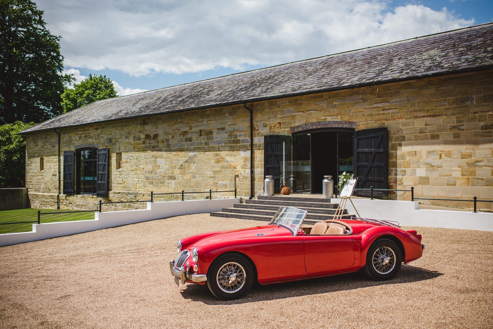 Stone barn at Hendall Manor Barns with a red vintage sports car parked outside