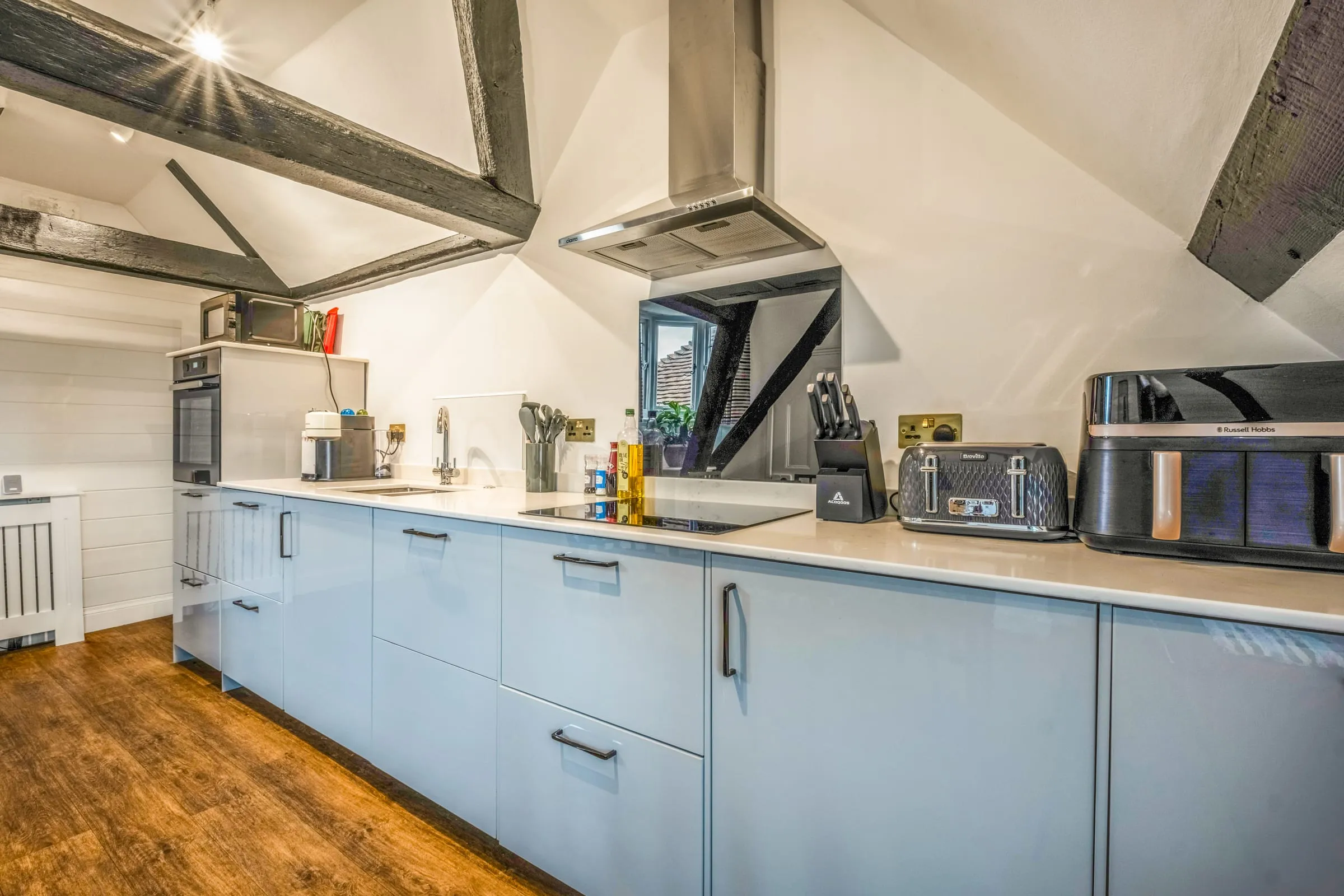 Kitchen worktop with induction hob, toaster, air fryer and coffee machine under sloping beamed ceiling