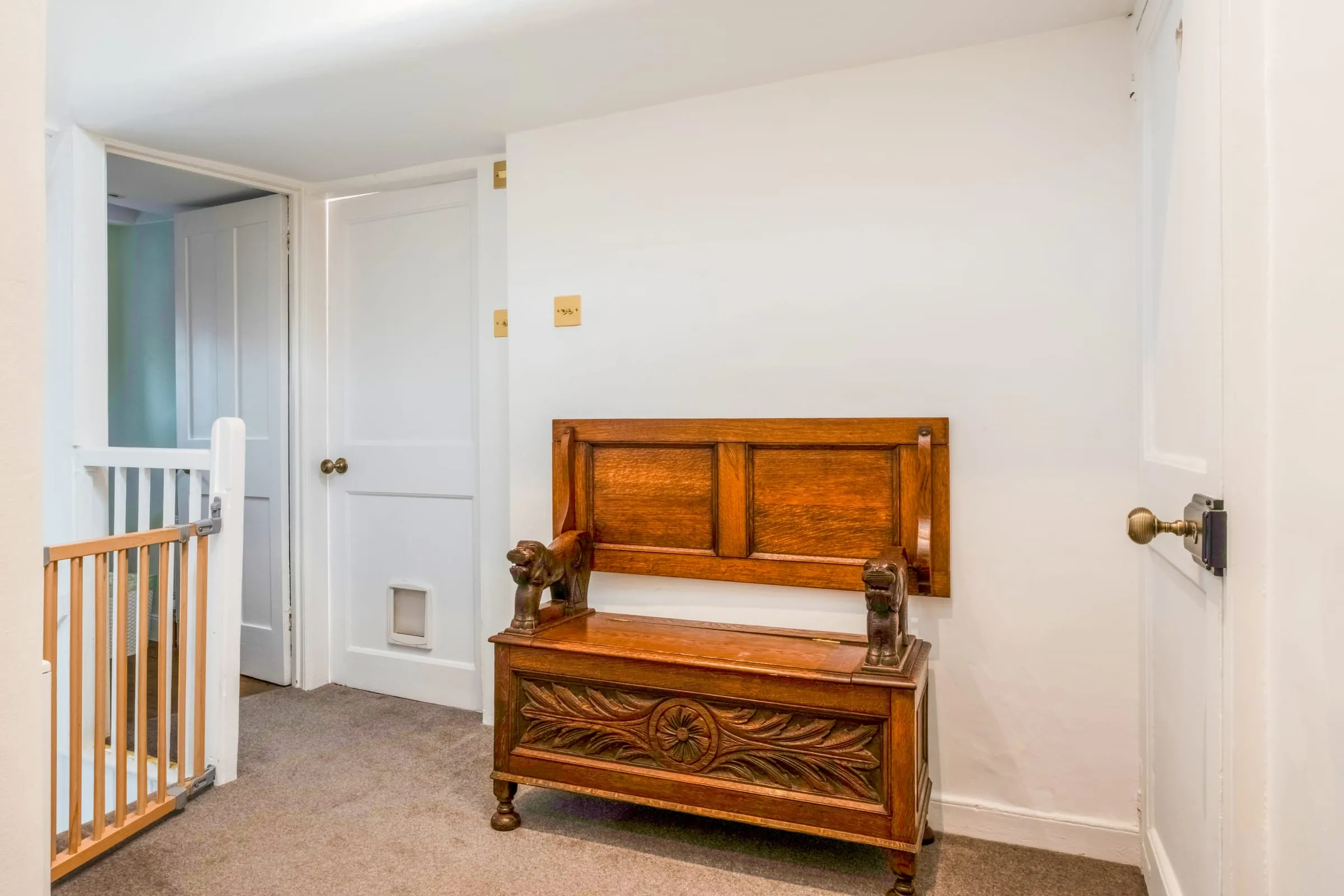 Landing with a carved oak bench and white panelled doors