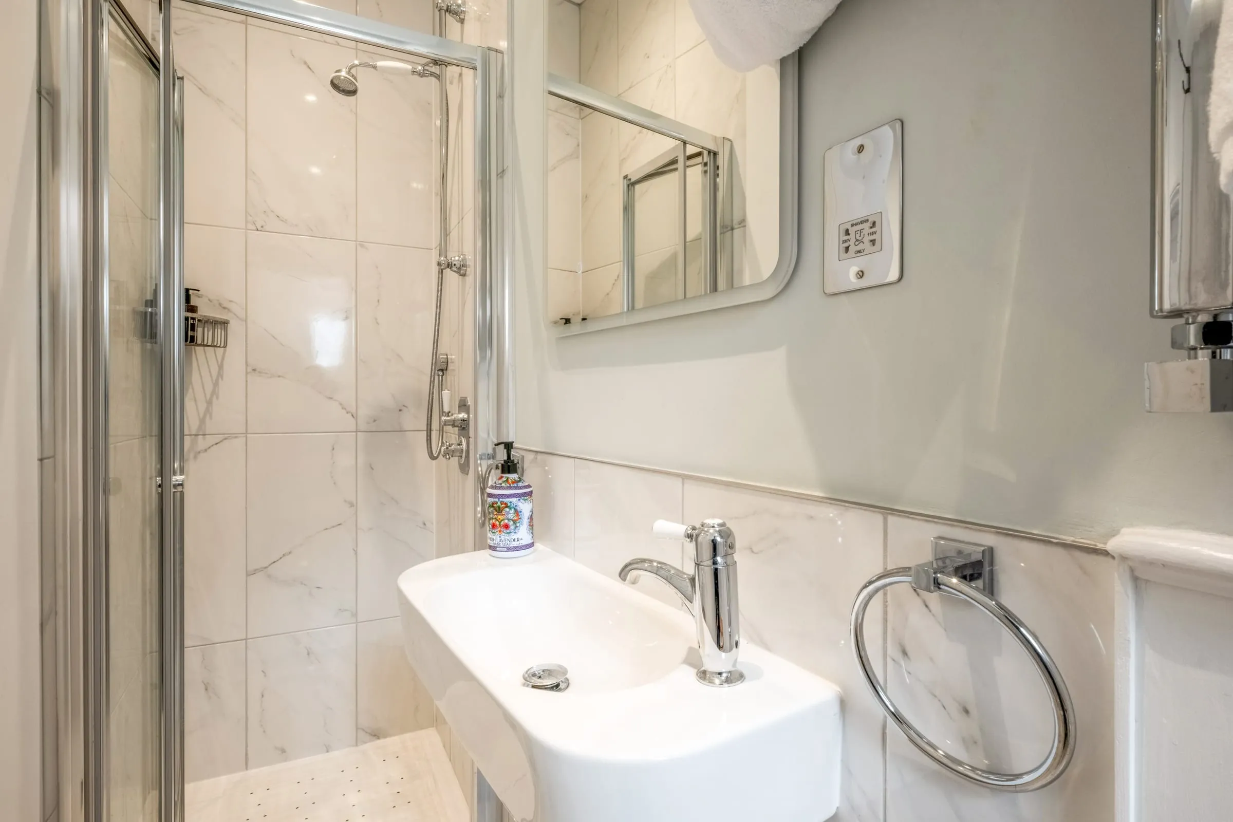 Compact shower room with glass shower enclosure, basin and mirror