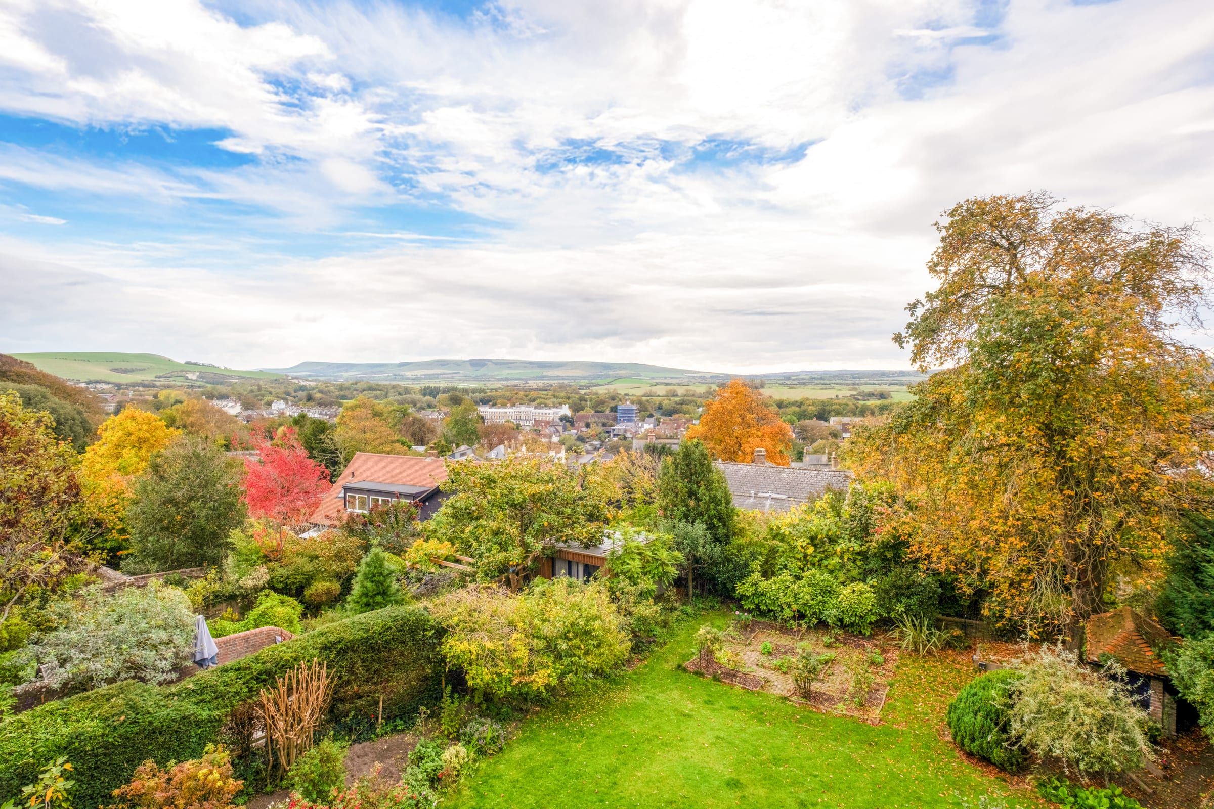 Rooftop view from the apartment over Lewes gardens and autumn trees to the South Downs under a blue sky